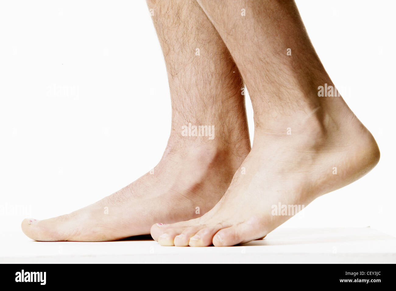 Cropped feet of male one foot with heel raised against white background