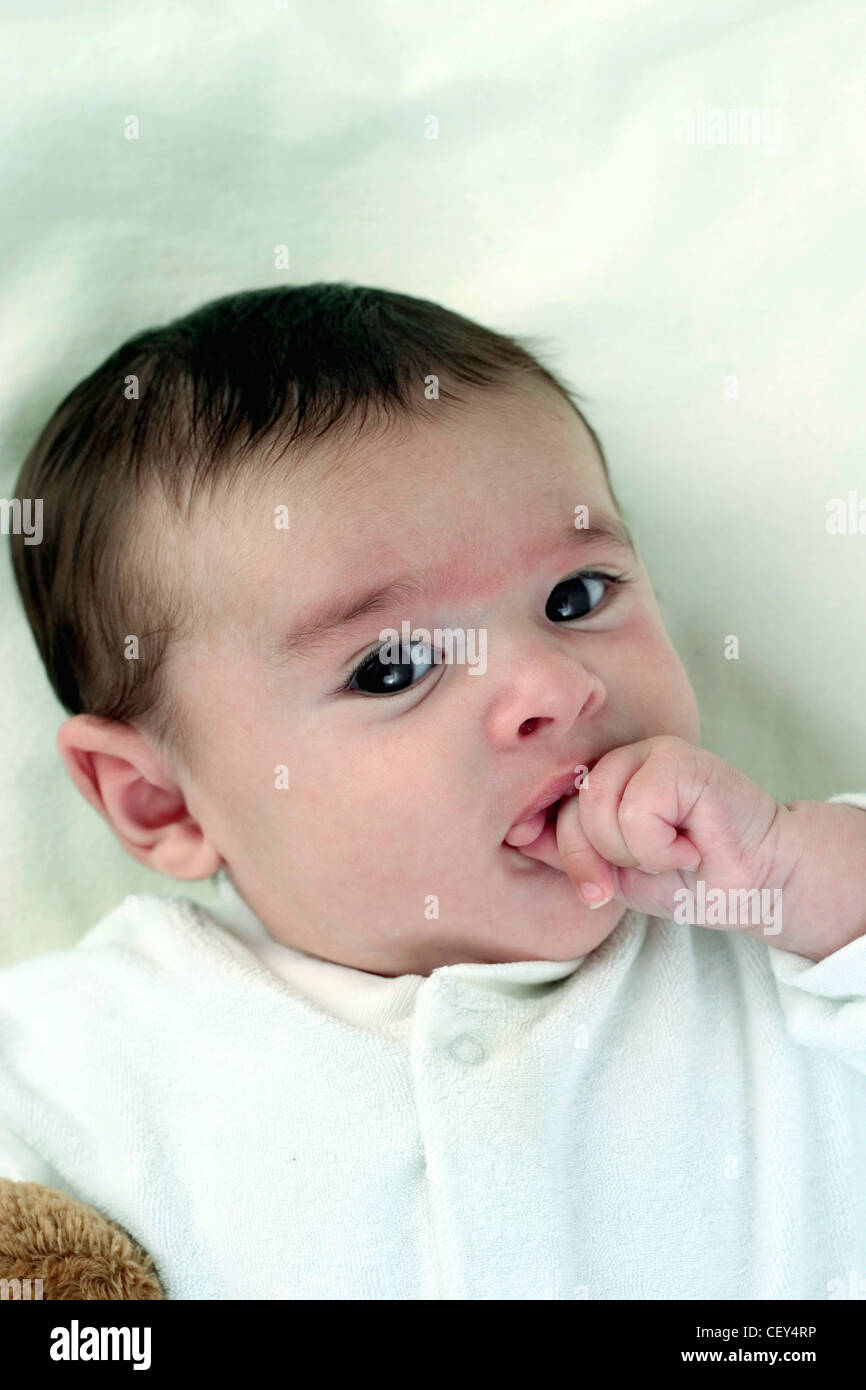 Male Child With Dark Brown Hair Wearing White Babygrow Looking Up At Stock Photo Alamy