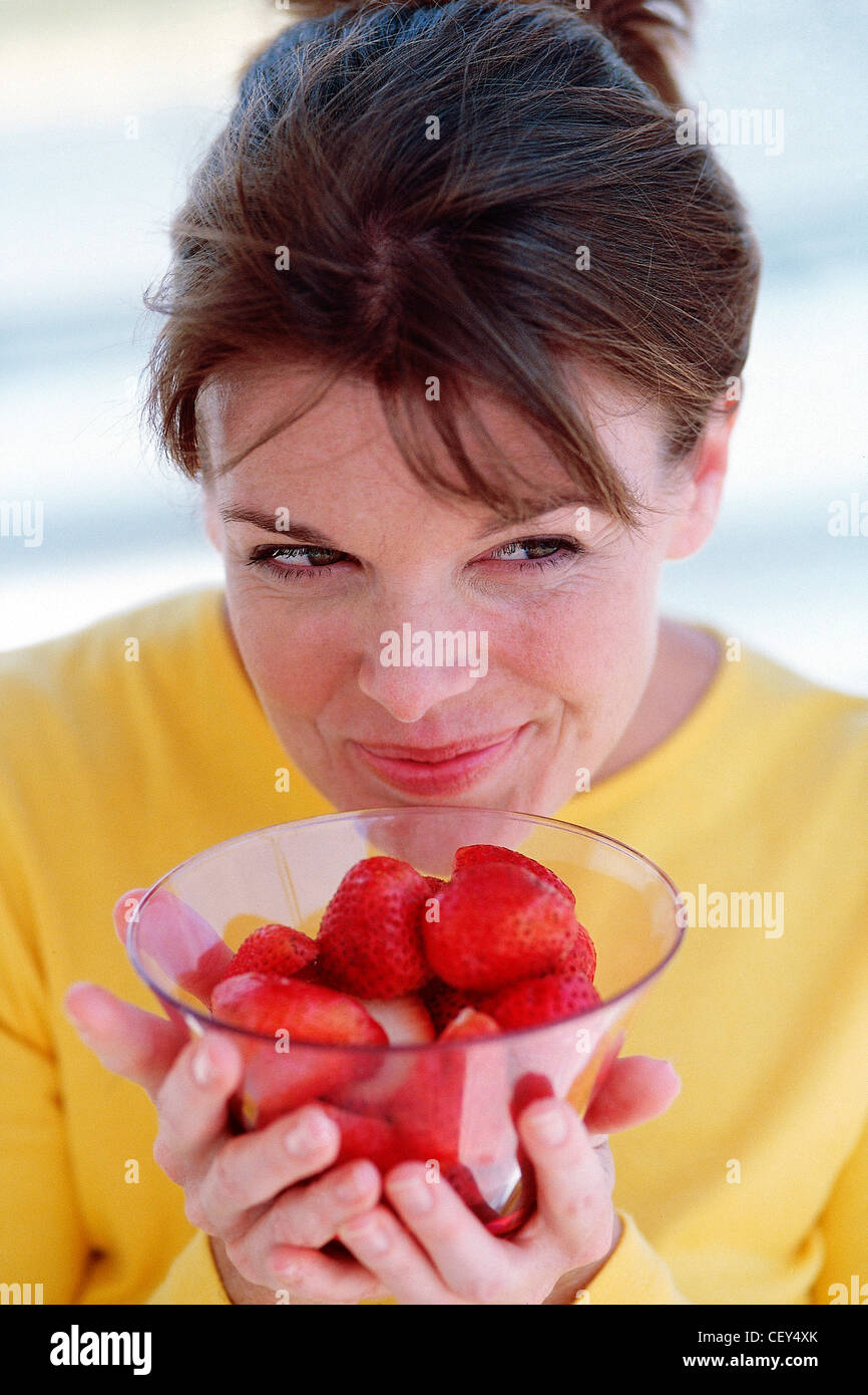 Female hair off face wearing yellow t shirt holding glass bowl
