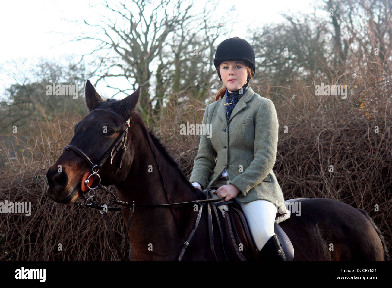 A red headed female teenager wearing cream jodhpurs, black riding boots