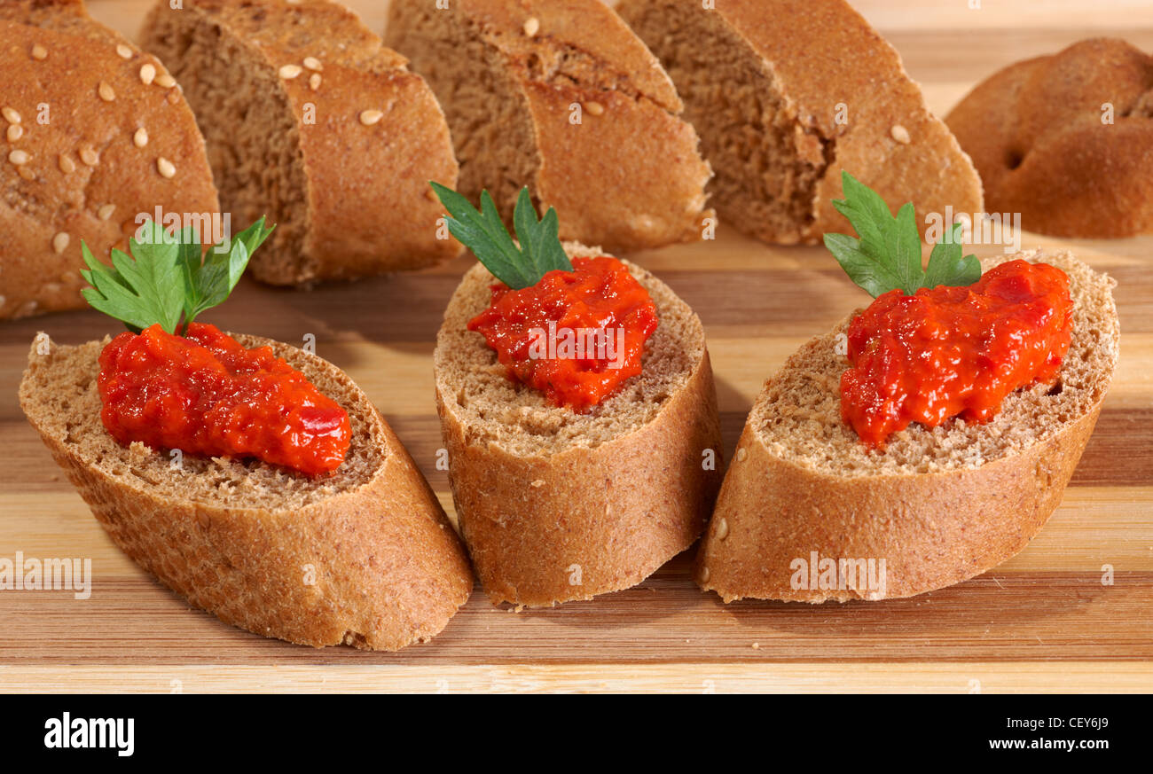 Red pepper ajvar puree on bread slices Stock Photo