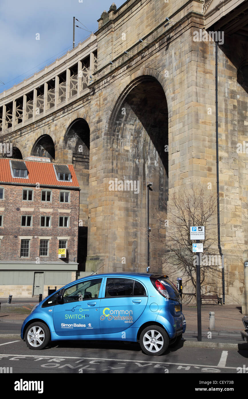 Peugeot Ion electric car being charged on Newcastle Quayside with Victorian rail bridge in the background Stock Photo