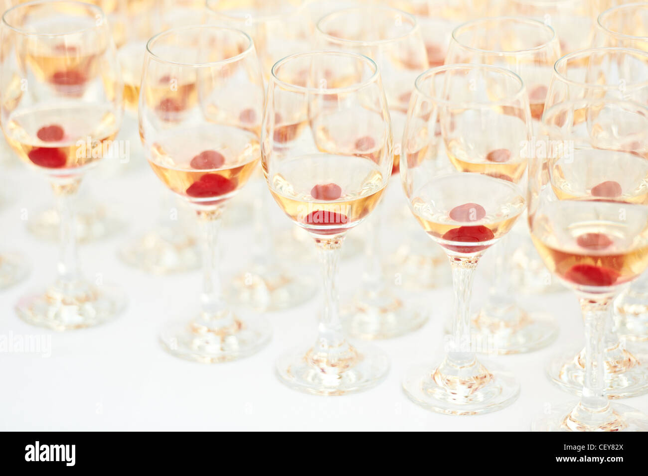Multiple party glasses with brandy and red cherry on table Stock Photo