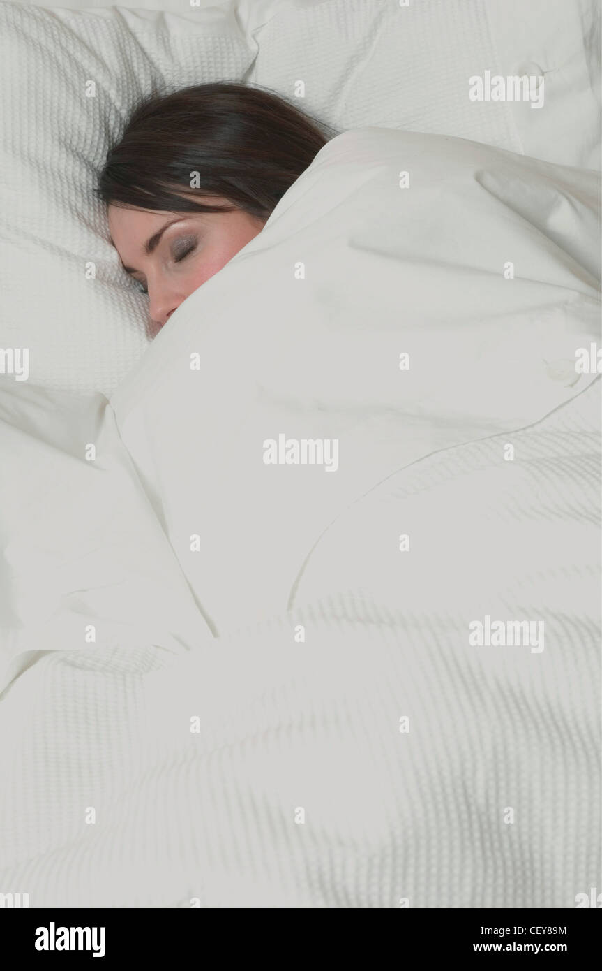 female in bed under a white duvet, sleeping Bottom half of