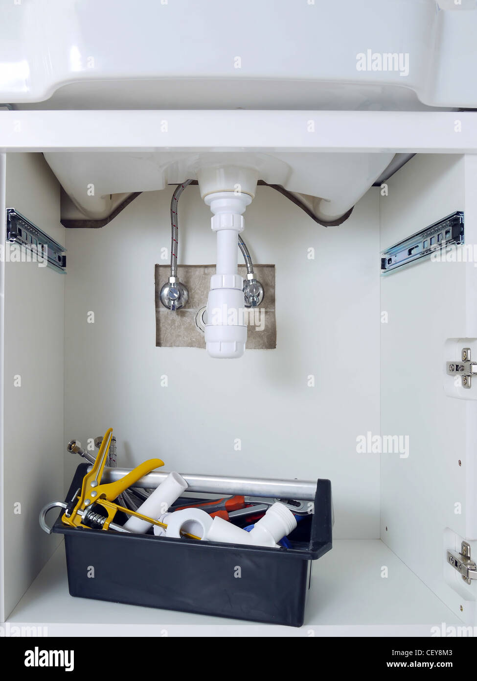 Bathroom cabinet with washbasin plumbing fixtures and plumber's toolbox Stock Photo