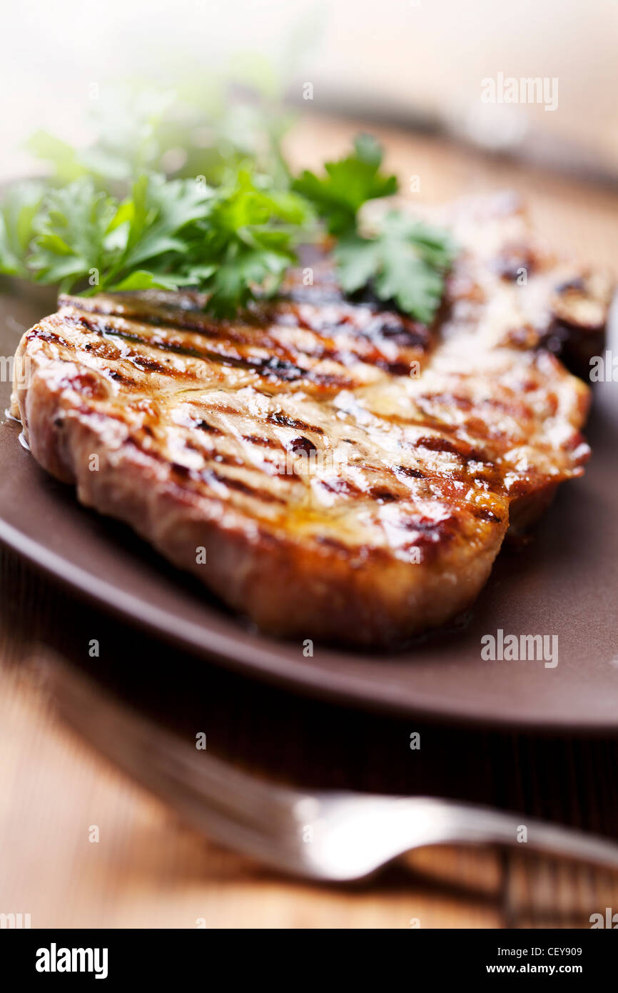 juicy grilled pork chop (neck cut) with greens Stock Photo