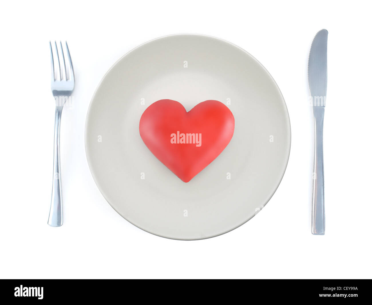 Red heart-on plate with fork and knife shot from above on white background Stock Photo