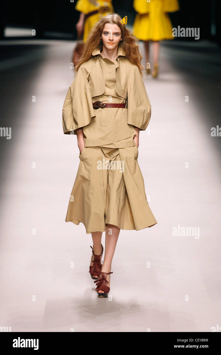 Voluminous plain khaki three piece with floaty midi skirt, worn with dark brown leather strappy platform shoes Stock Photo