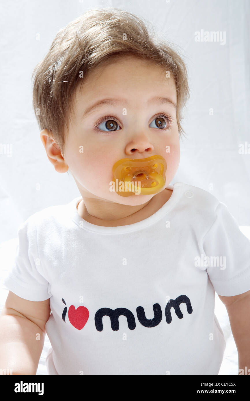 Female baby with dummy in mouth wearing T shirt with I love mum