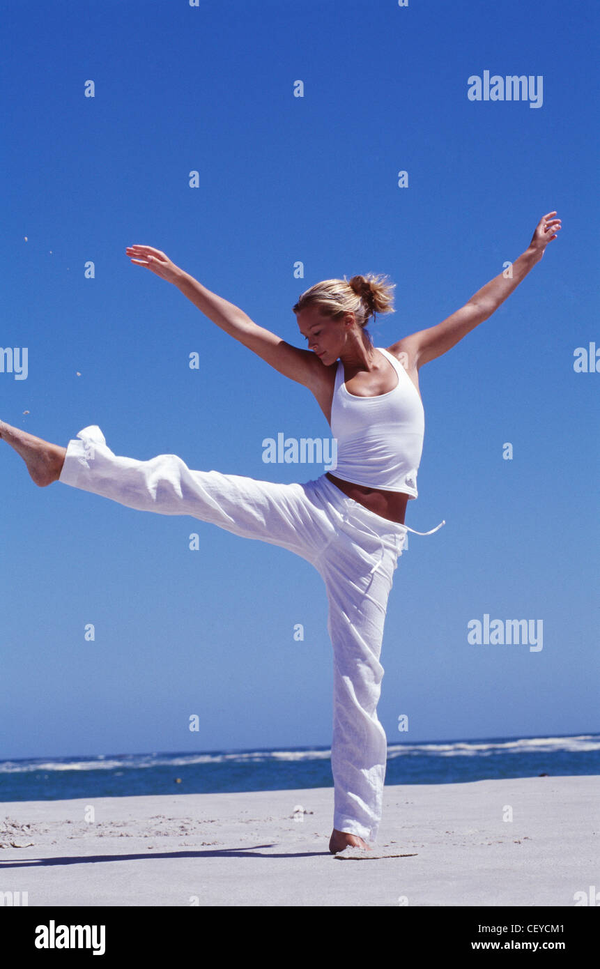 Female on beach kicking leg high up in air Stock Photo