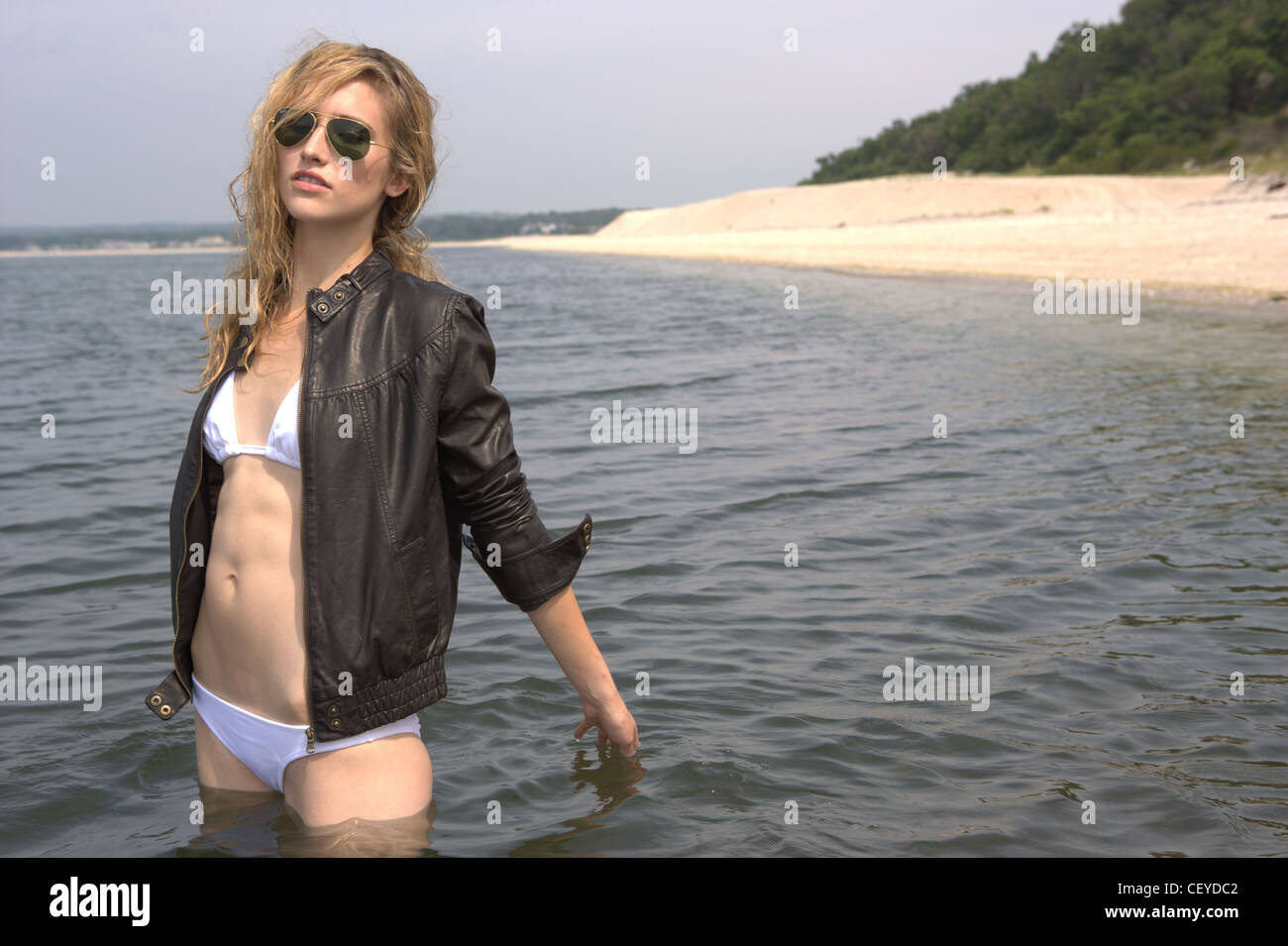Female wearing white bikini, brown leather jacket and aviatsunglasses