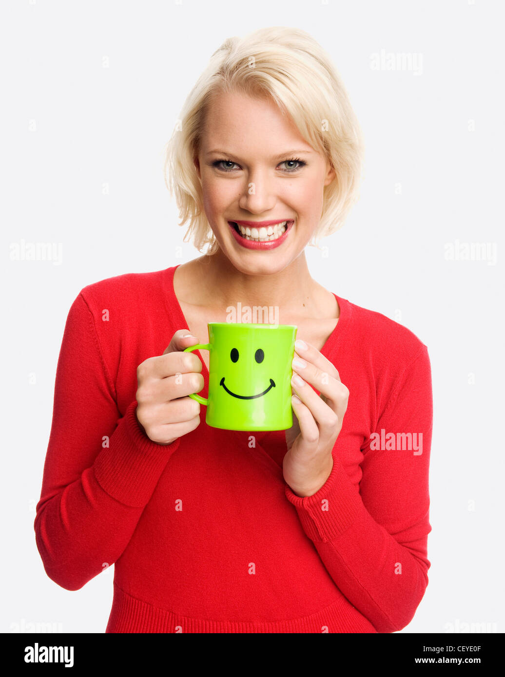 Female holding a green mug with a smiley face Stock Photo