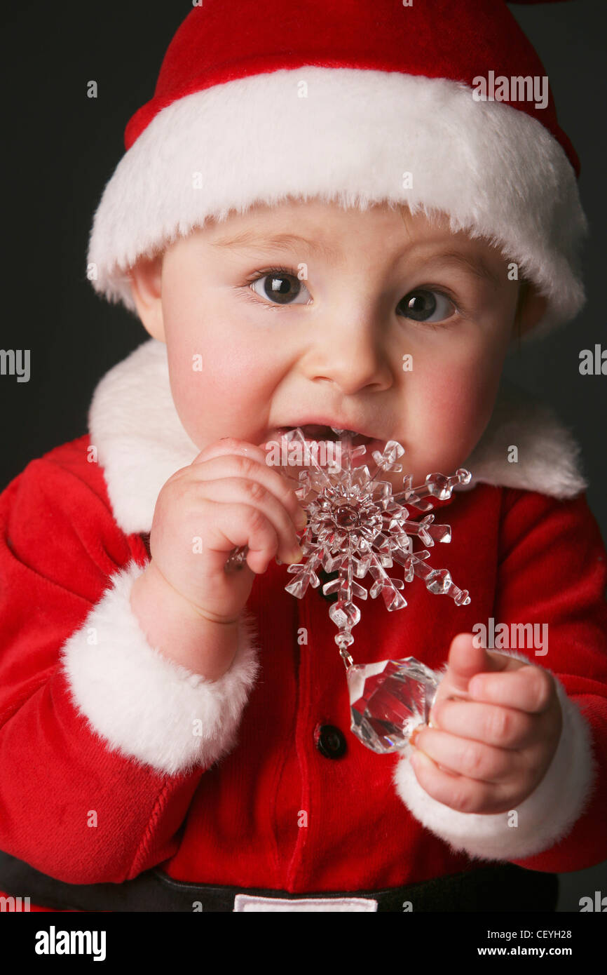 baby in a santa claus outfit chewing on an ornament edmonton alberta canada Stock Photo Alamy