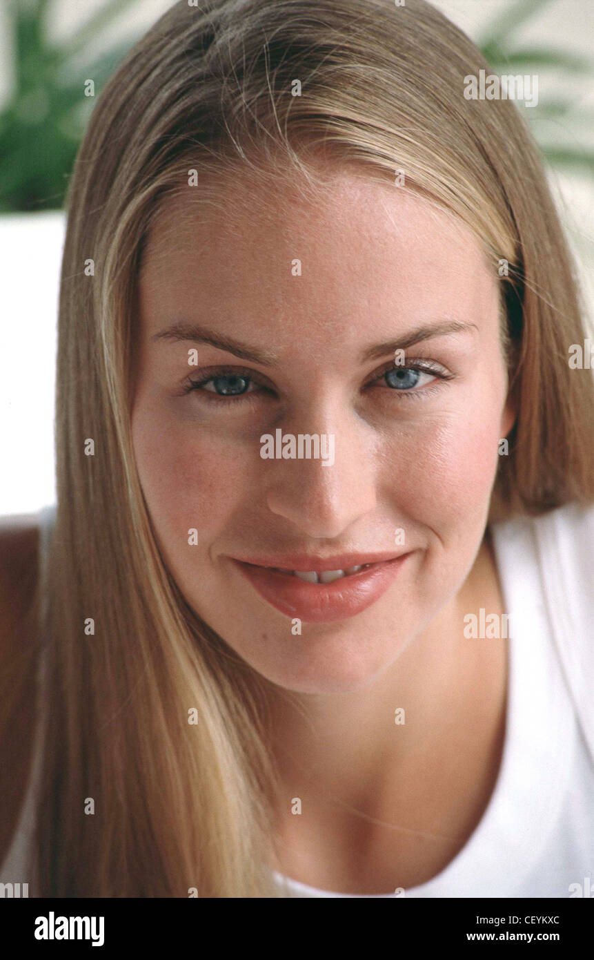 Female with long fair hair wearing white vest top subtle make up and lip gloss looking to camera smiling Stock Photo