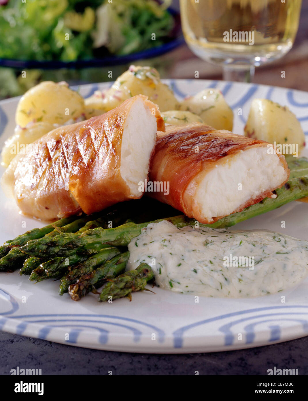 White and blue plate grilled white fish fillet wrapped in parma ham cut