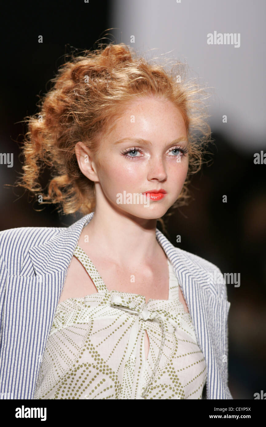 Model Lily Cole curly red hair off face wearing searsucker blue and white striped blazer over white vest kahki green pattern of Stock Photo