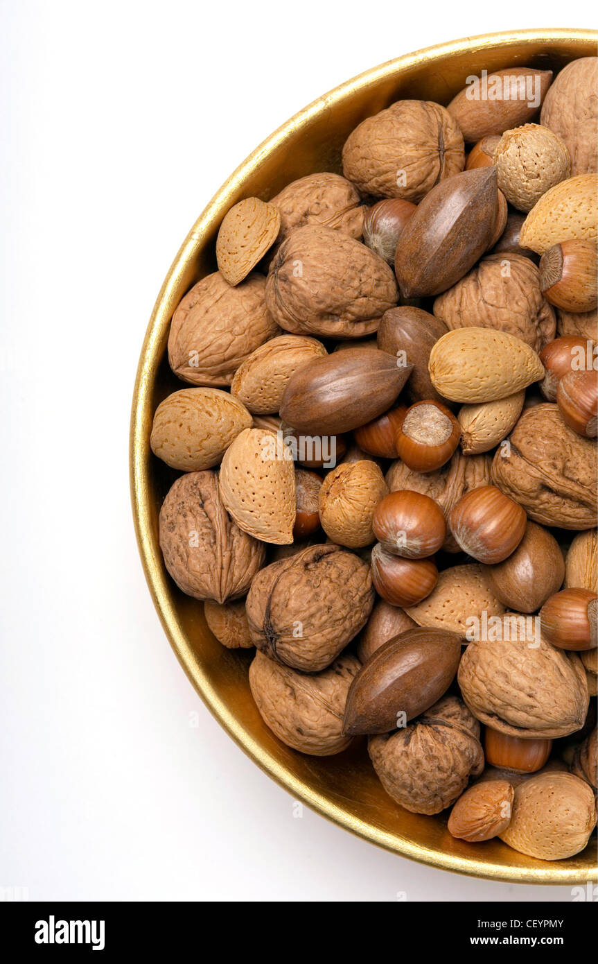 A gold bowl of mixed nuts in their shells, including almonds, hazelnuts