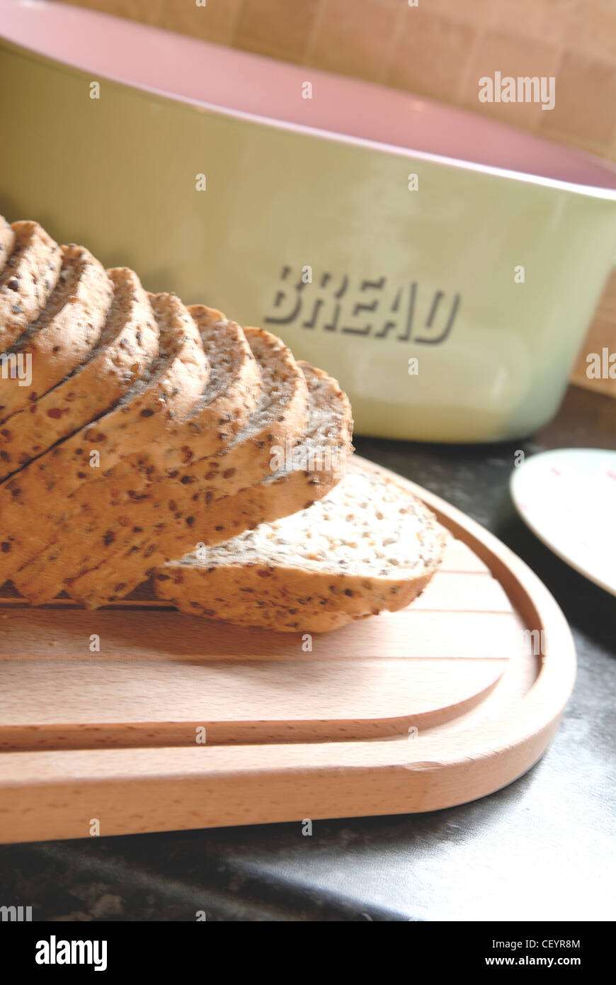 A retro bread bin with a wooden chopping board with a loaf of sliced