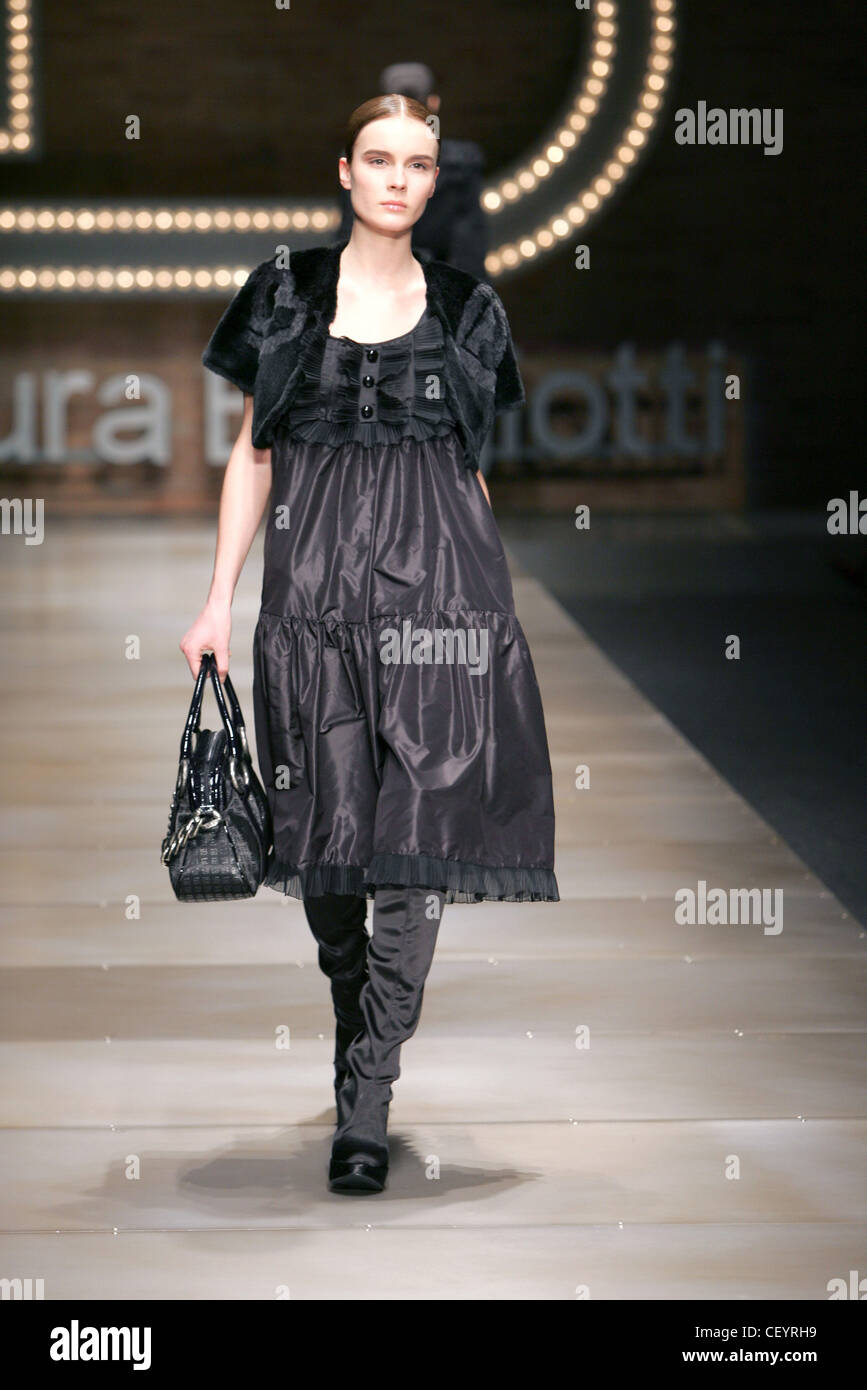 Laura Biagiotti Milan Fashion Week Autumn Winter Model wearing black satin loose layered dress sheer ribbon ruffled hem, Stock Photo