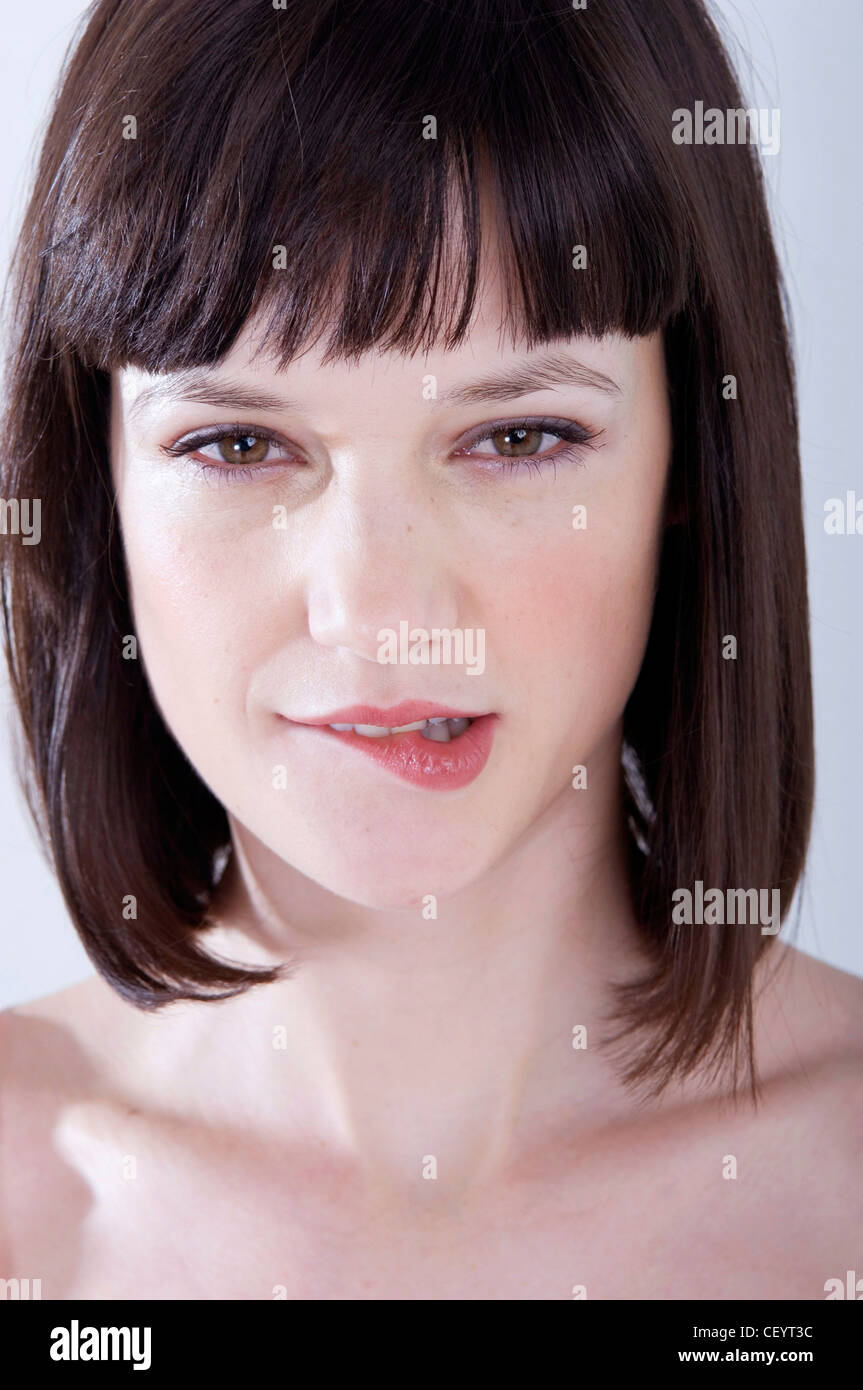Portrait of female with brunette hair in bob looking straight to camera biting lip  RBO Stock Photo