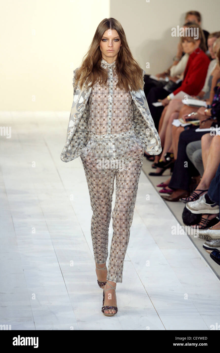 Model wearing sheer grey geometric patterned trousers and matching shirt a grey pattnered jacket, and sequin covered sandals Stock Photo