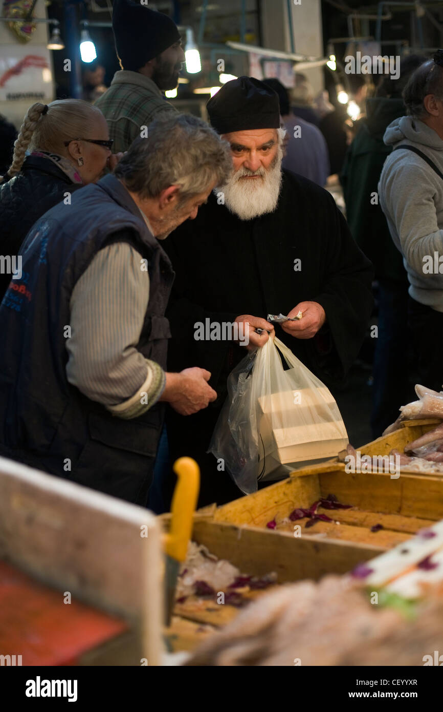A Greek Orthodox priest buys seafood from a stall in the Athens Central Market on Athinas Street. Athens, Greece Stock Photo