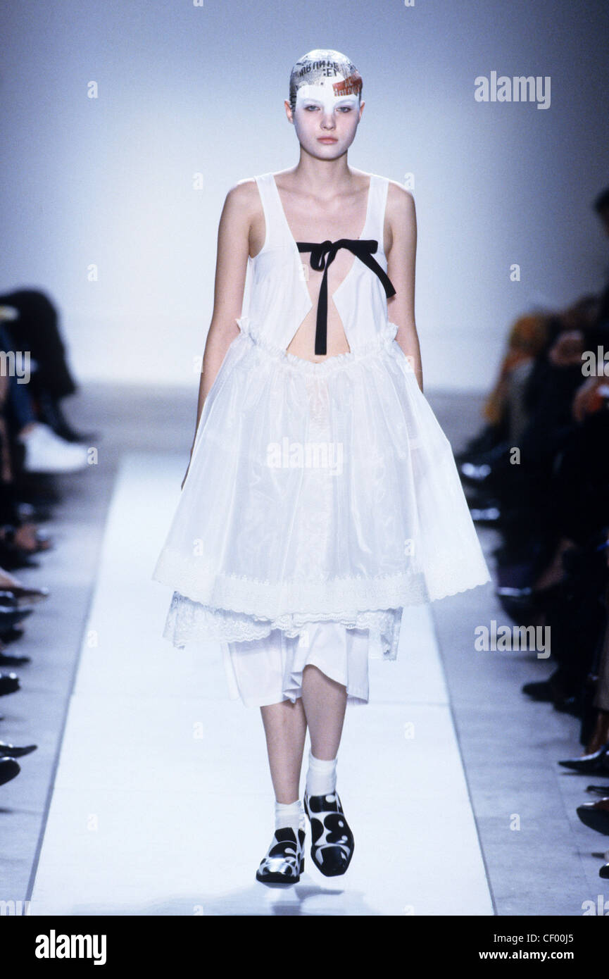 Commes de Garcons Spring Summer Monochrome: long white baby doll dress tied at the check black ribbon, white socks and print Stock Photo