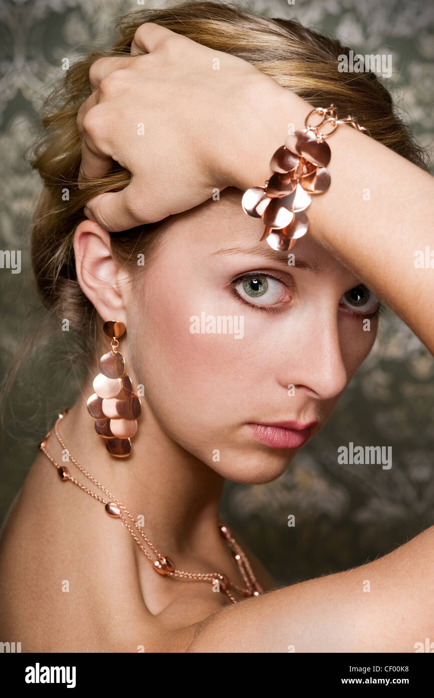 elegant woman wearing golden necklace and earrings, over wallpaper background Stock Photo