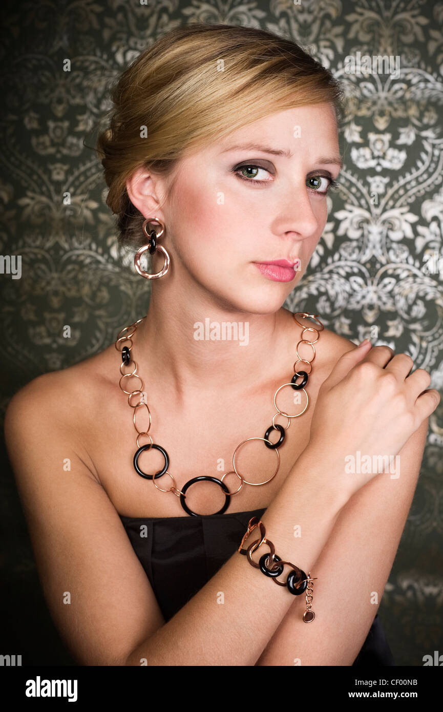 elegant woman wearing golden necklace and earring, over wallpaper background Stock Photo