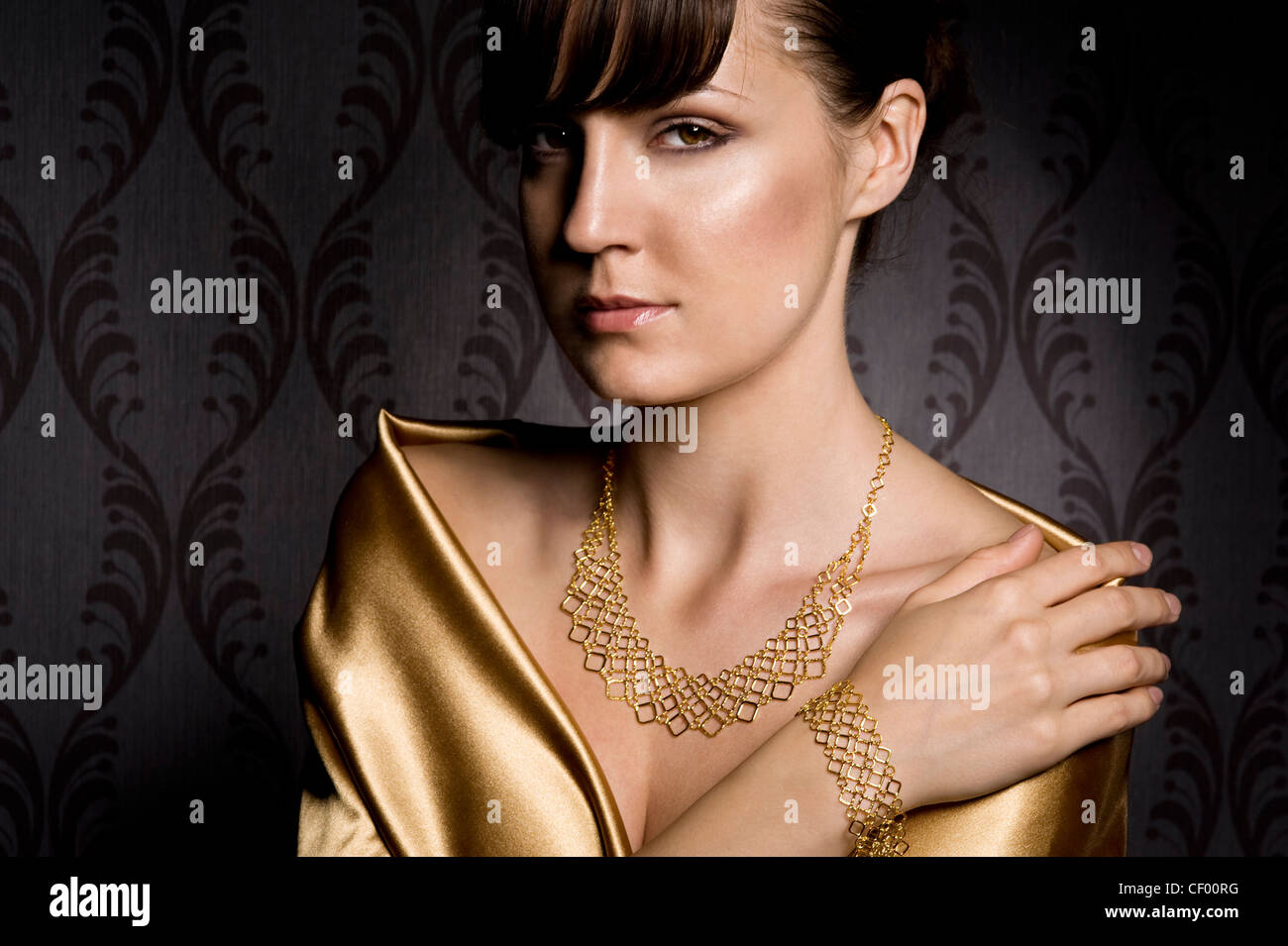 portrait of elegant woman wearing golden necklace and bracelet, over wallpaper background Stock Photo