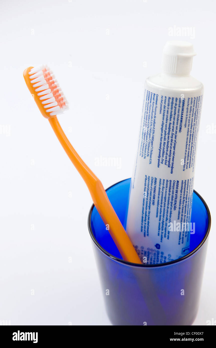 A blue glass with a tube of toothpaste and a yellow toothbrush in it Stock  Photo - Alamy