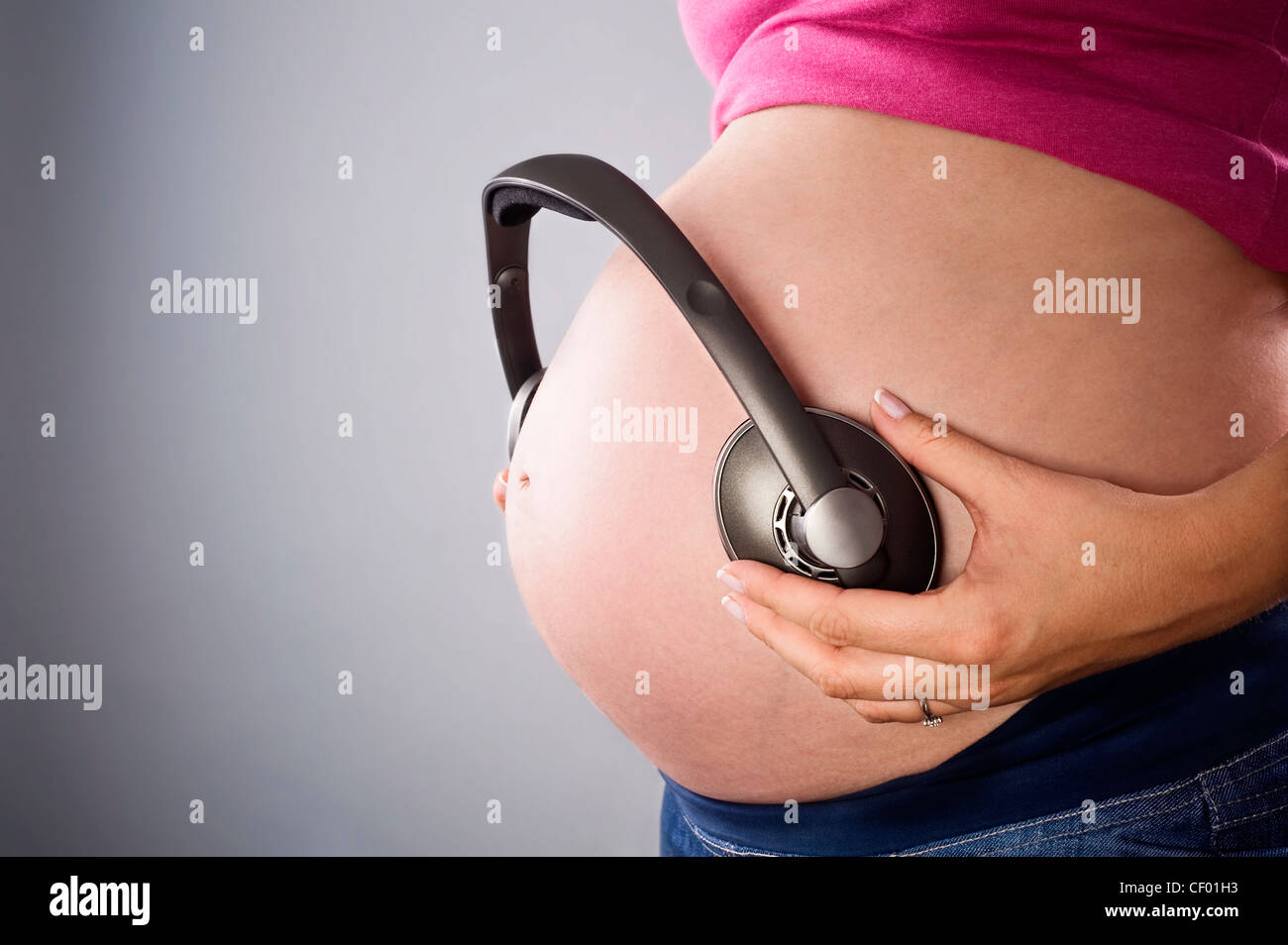 pregnant belly and earphones over gray background Stock Photo