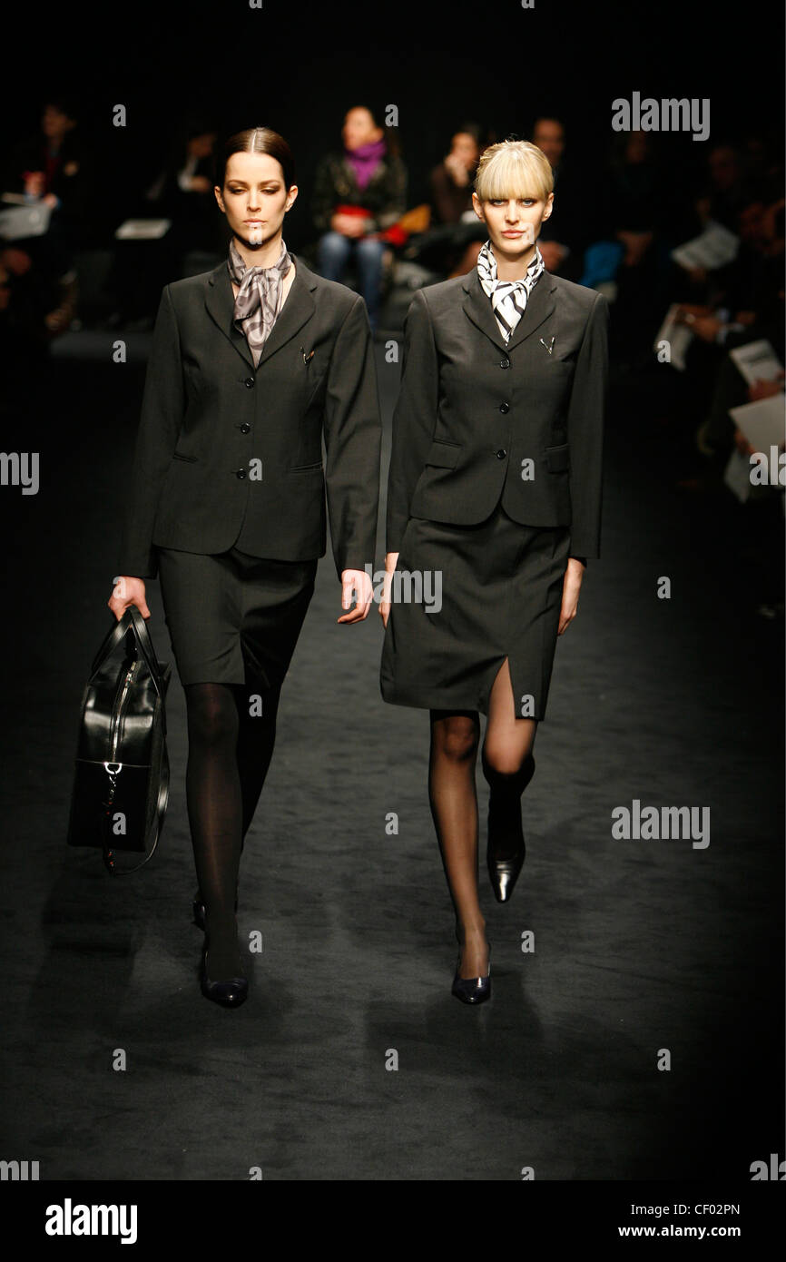 Valentino Menswear Milan A W A blonde and brunette female walking together gether wearing typical black flight attendant suits Stock Photo