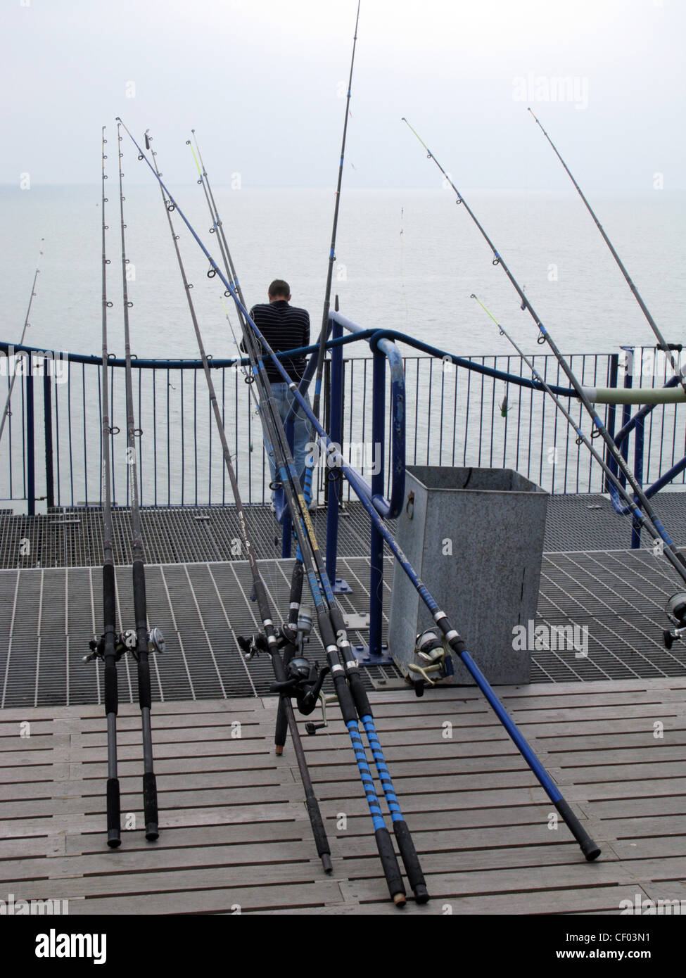 Sea angling. An angler with lots of fishing rods on the pier at