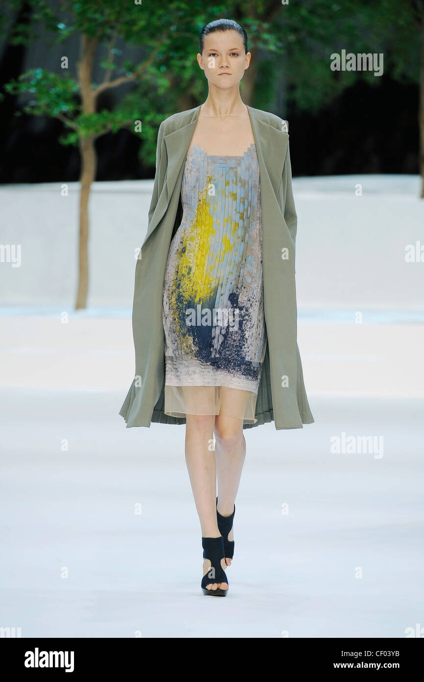 Akris Paris Ready to Wear Spring Summer Model wearing a pleated georgette graphic printed dress a grey coat and black cut out Stock Photo