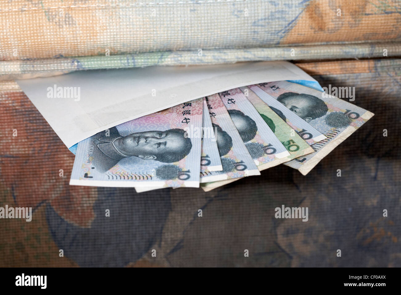 hiding chinese renminbi cash in an envelope under the mattress Stock Photo