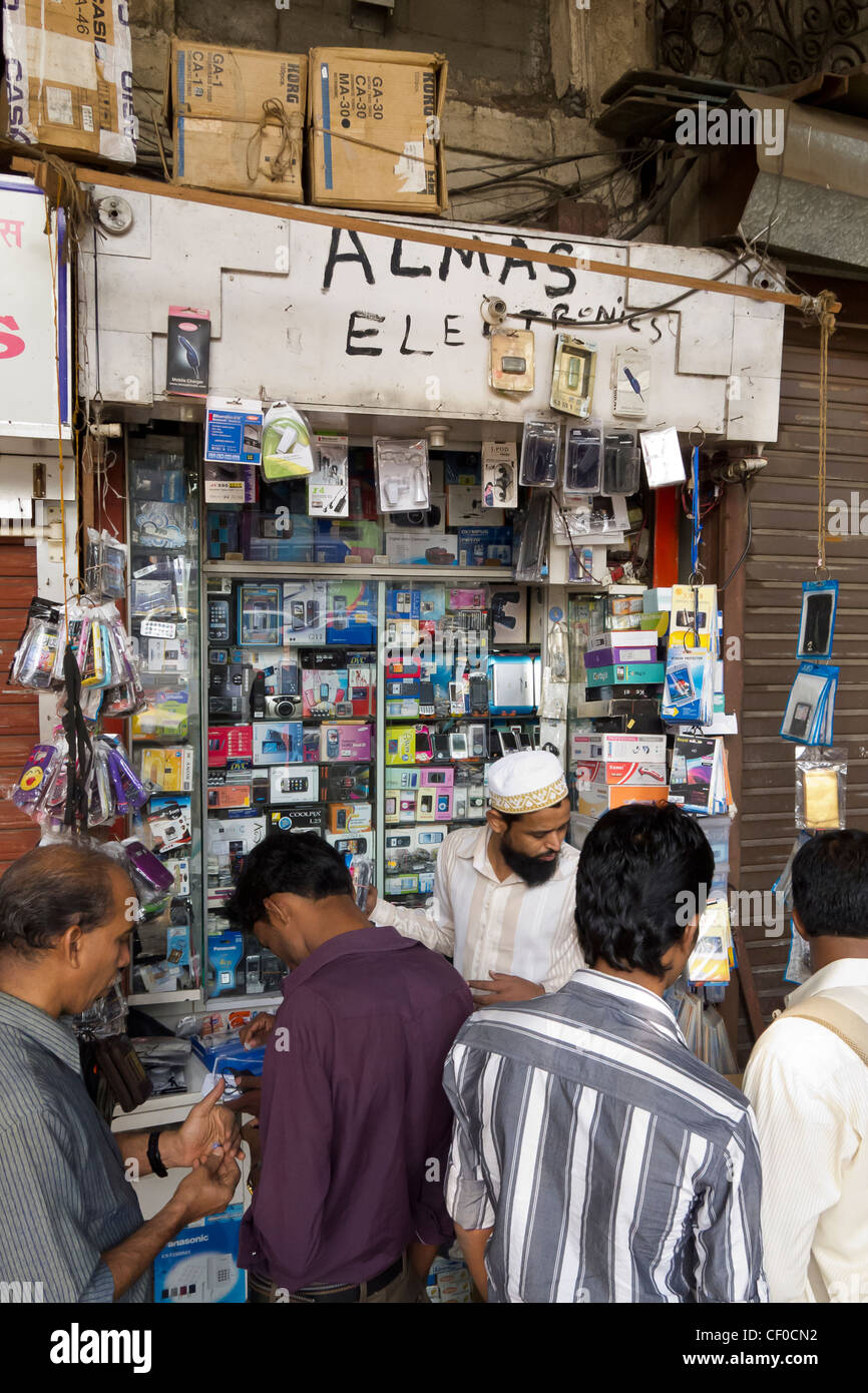 a small hole in the wall shop in Mumbai with shopkeeper and customers transacting business, Maharashtra, India Stock Photo