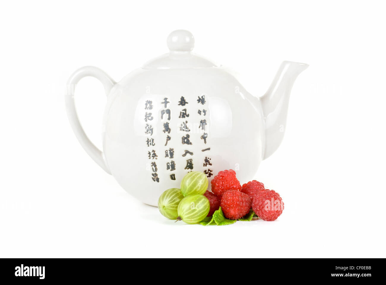 Teapot with fruit tea and berries on a white background Stock Photo