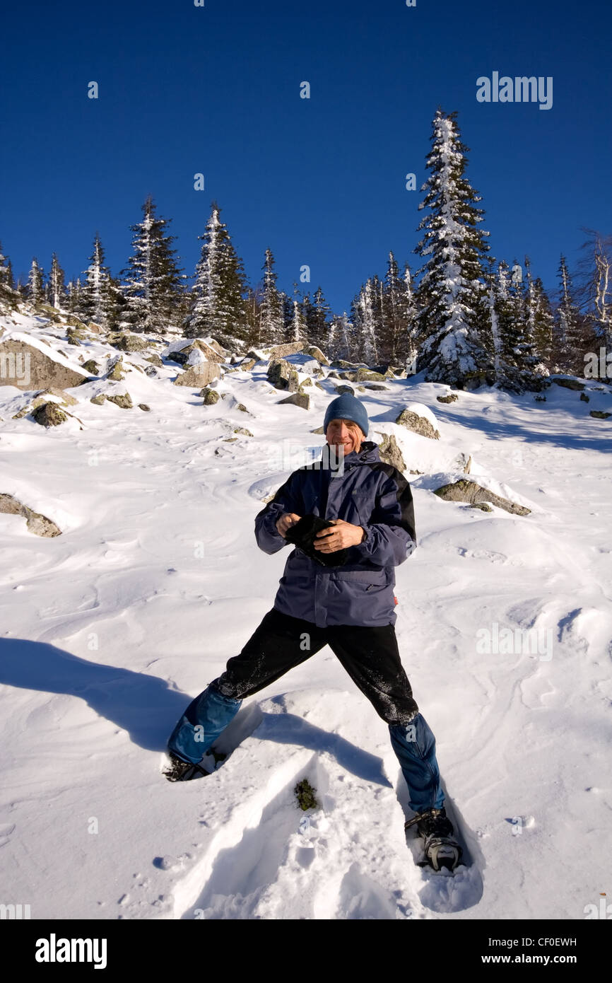 Climber in snowshoes (snow shoes) at the mountain slope. Winter forest. Russia. Ural mountains. National park Taganay. Stock Photo