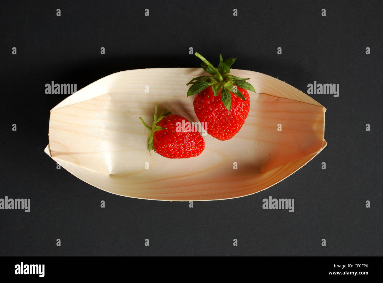 Two fresh strawberries in wood plate on dark gray background Stock ...