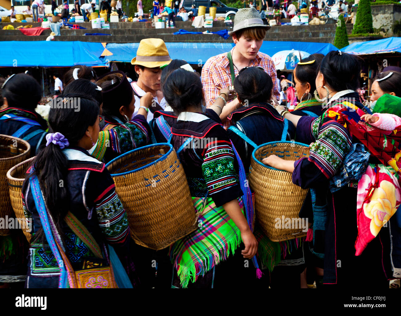 Hmong tribe girls attempting to sell souvenirs to a couple of tourists in a market in Sapa, Vietnam Stock Photo