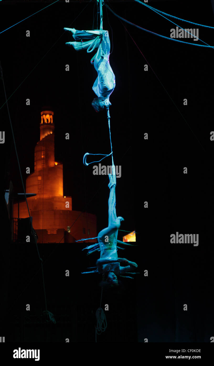 Trapeze artists  perform for the Doha Spring Festival at a stage in Souq Waqif, Doha, Qatar, in front of a spiral minaret Stock Photo