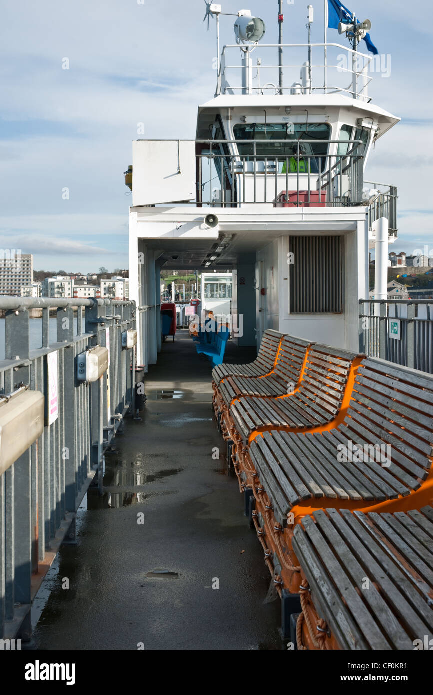 Top deck of a small car ferry with wooden seats in a row. Stock Photo