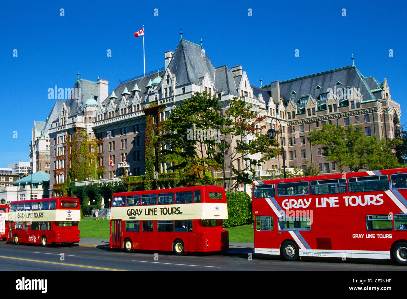 Double-decker tour buses line up in front of the regal Empress Hotel,  a landmark since 1908 on Vancouver Island in Victoria, British Columbia, Canada. Stock Photo