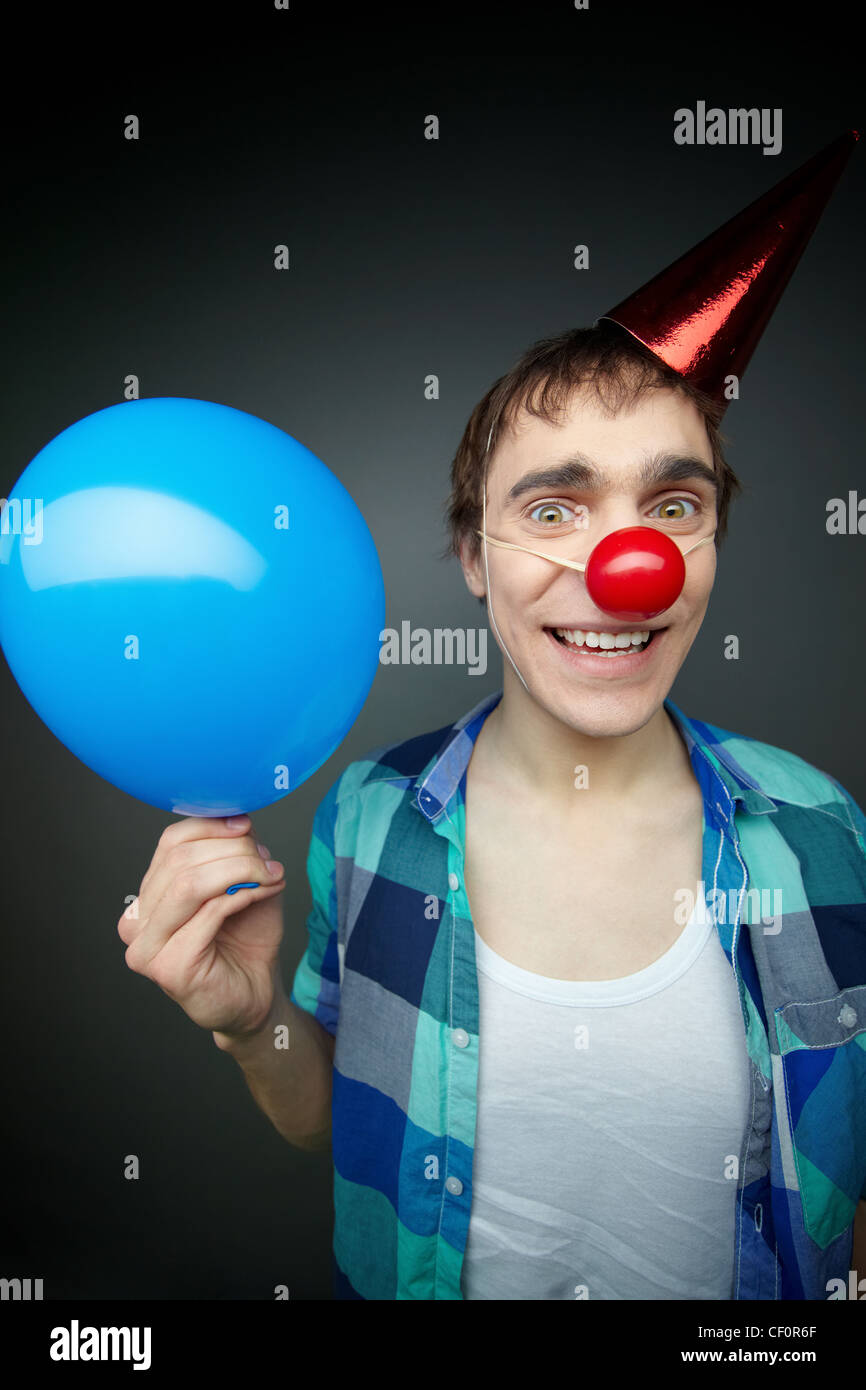 Happy guy holding a balloon and smiling crazily at camera celebrating fool’s day Stock Photo