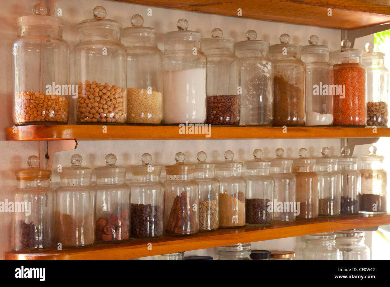 Shelves in house kitchen full of glass storage jars full of cooking ingredients Stock Photo