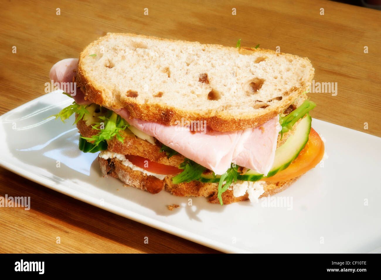 A triple decker ham and salad sandwich made with granary bread on a white plate. Stock Photo