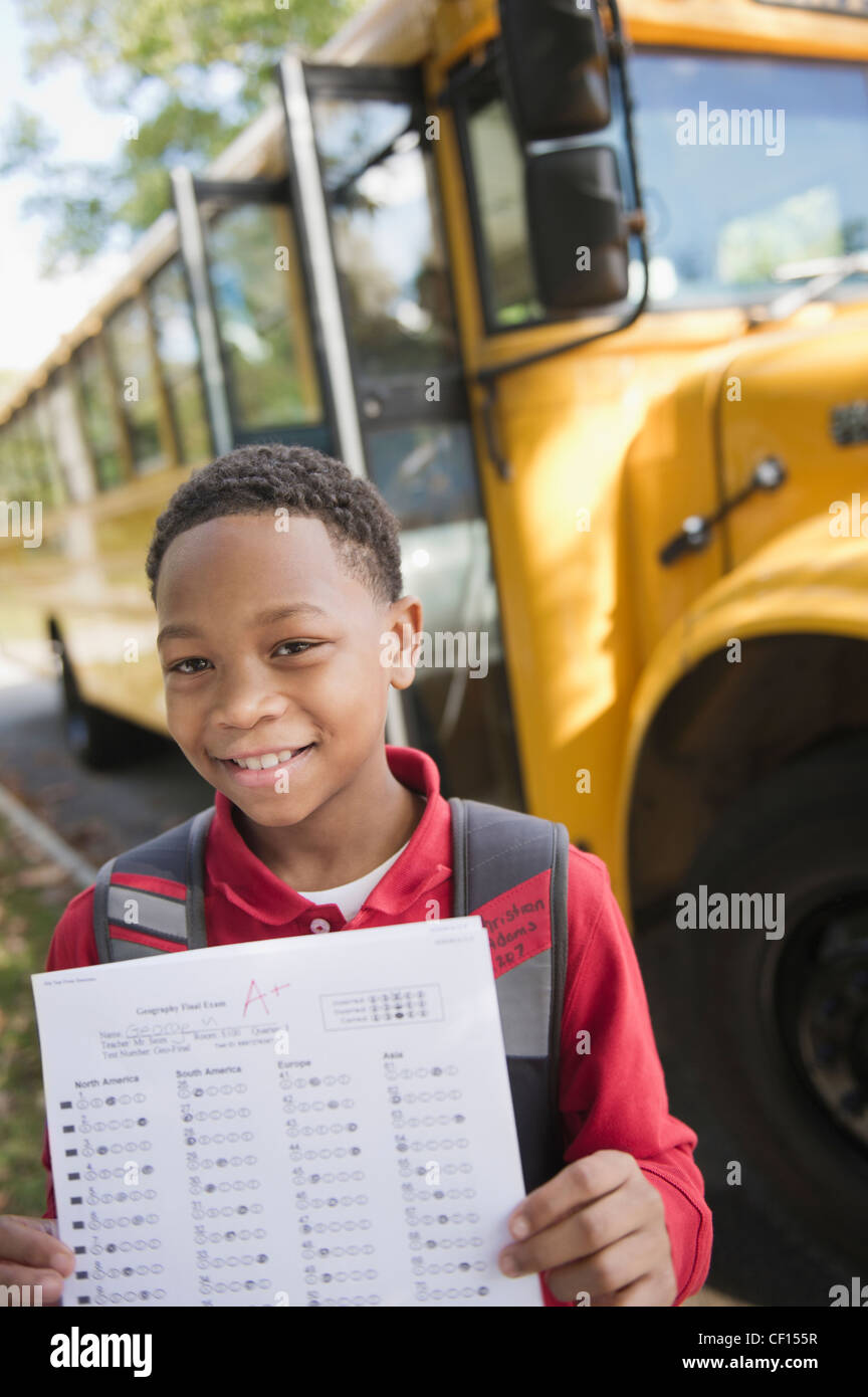 Mixed race boy holding test near school bus Stock Photo Alamy