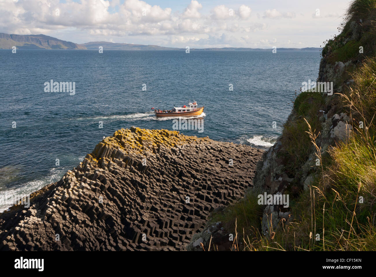 Boat departing from the Isle of Staffa on a site seeing sea cruise with Ulva in the background Stock Photo