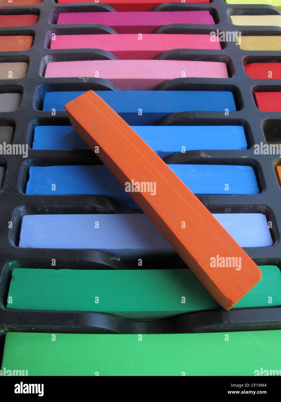 New unused chalk pastels in a box with a red one lying on top. Stock Photo
